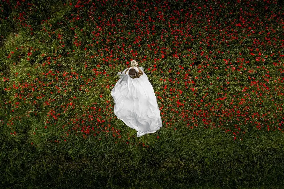 Novia tumbada en un campo de amapolas fotografiada con dron por Josu Izarra