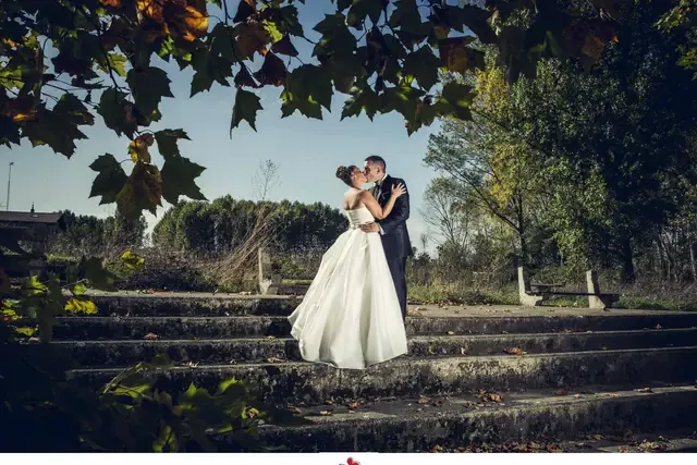 Novios besándose sobre escaleras de piedra en un parque en otoño, boda de Josu Izarra