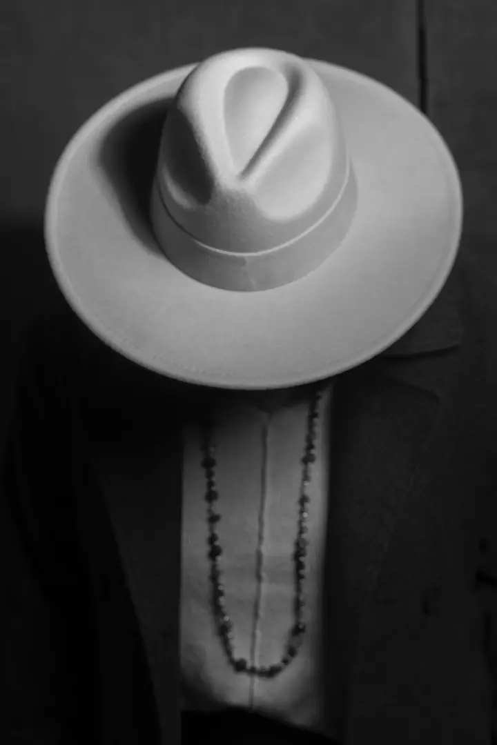 Retrato de autor en blanco y negro con sombrero claro y rosario, por Josu Izarra